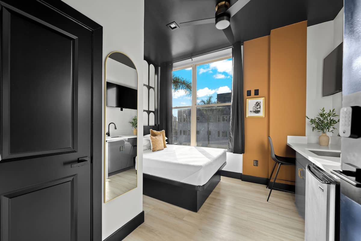 Un dormitorio moderno con una cama grande, un escritorio y una ventana con vistas a la ciudad.