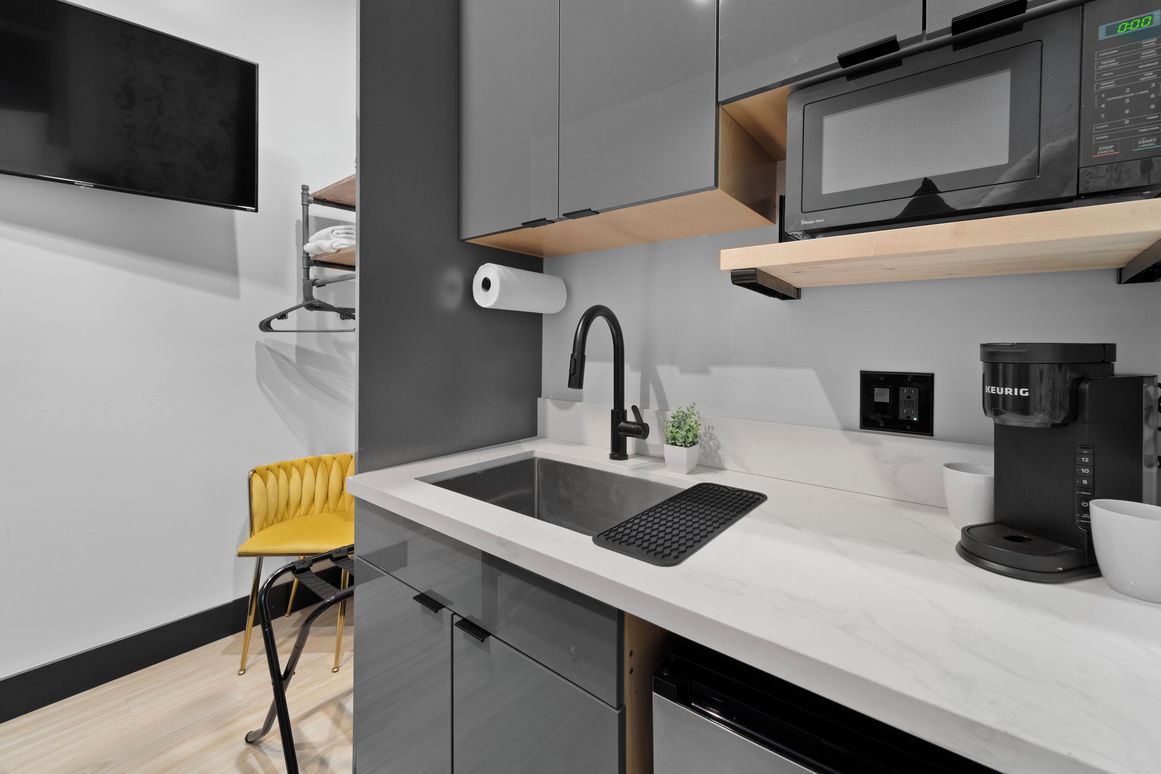 A modern kitchen with a built-in microwave, coffee maker, and a sink with a black faucet.