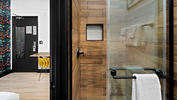 Un baño moderno con cabina de ducha de vidrio, revestimiento de pared de madera y un perchero para toallas.