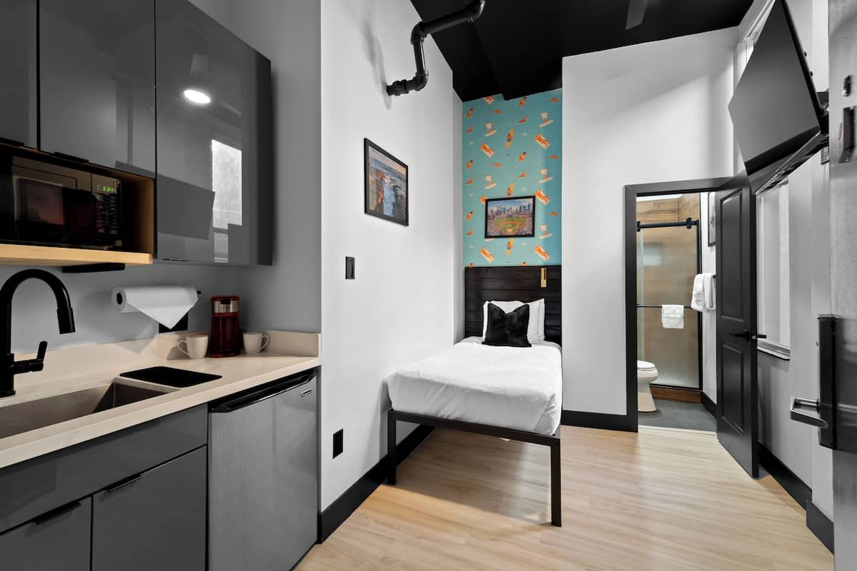 Una habitación de hotel compacta con kitchenette, una cama y un baño.
