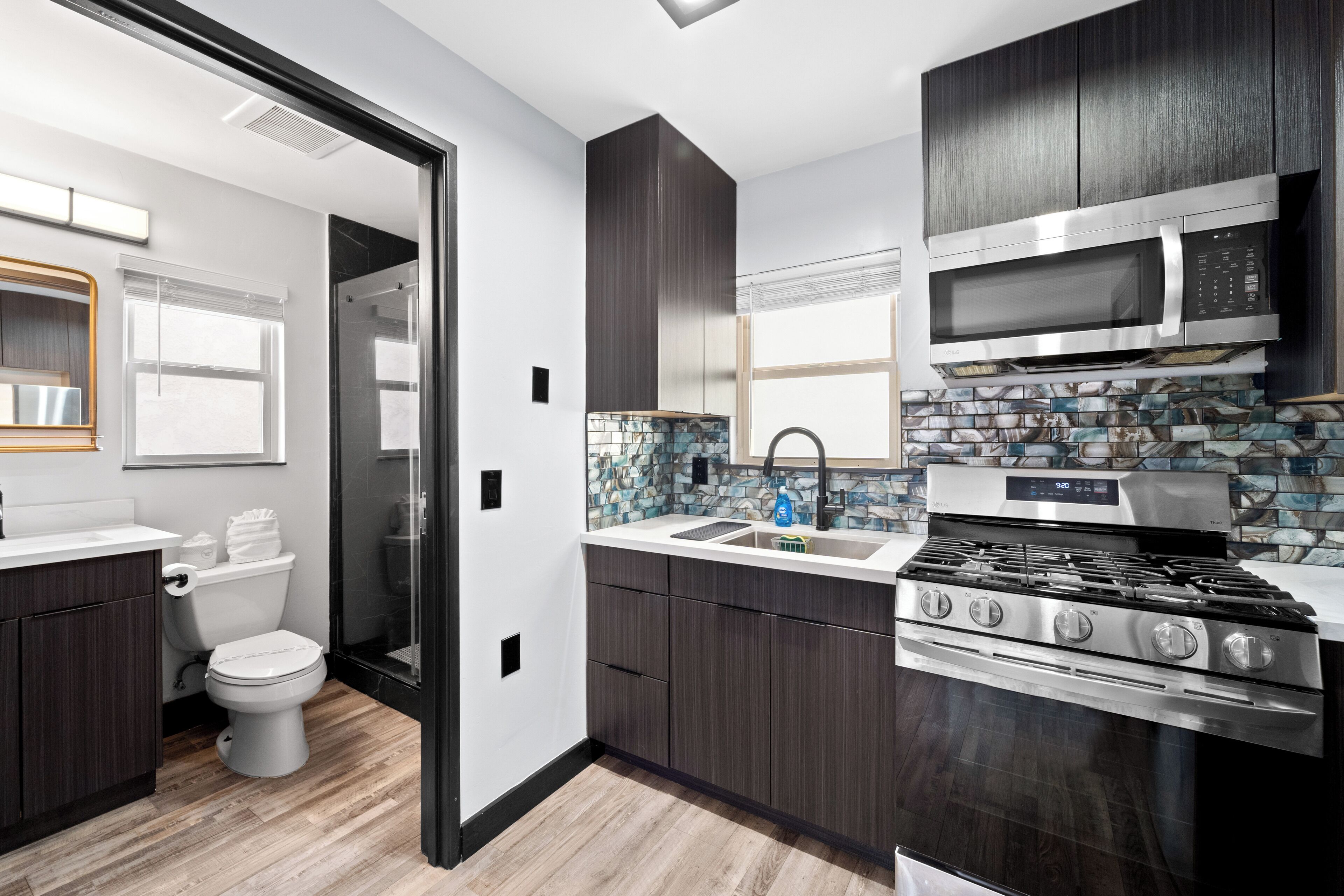 A modern kitchen with dark wood cabinets, a stainless steel stove, and a microwave.