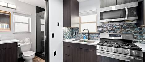 A modern kitchen with dark wood cabinets, a stainless steel stove, and a microwave.