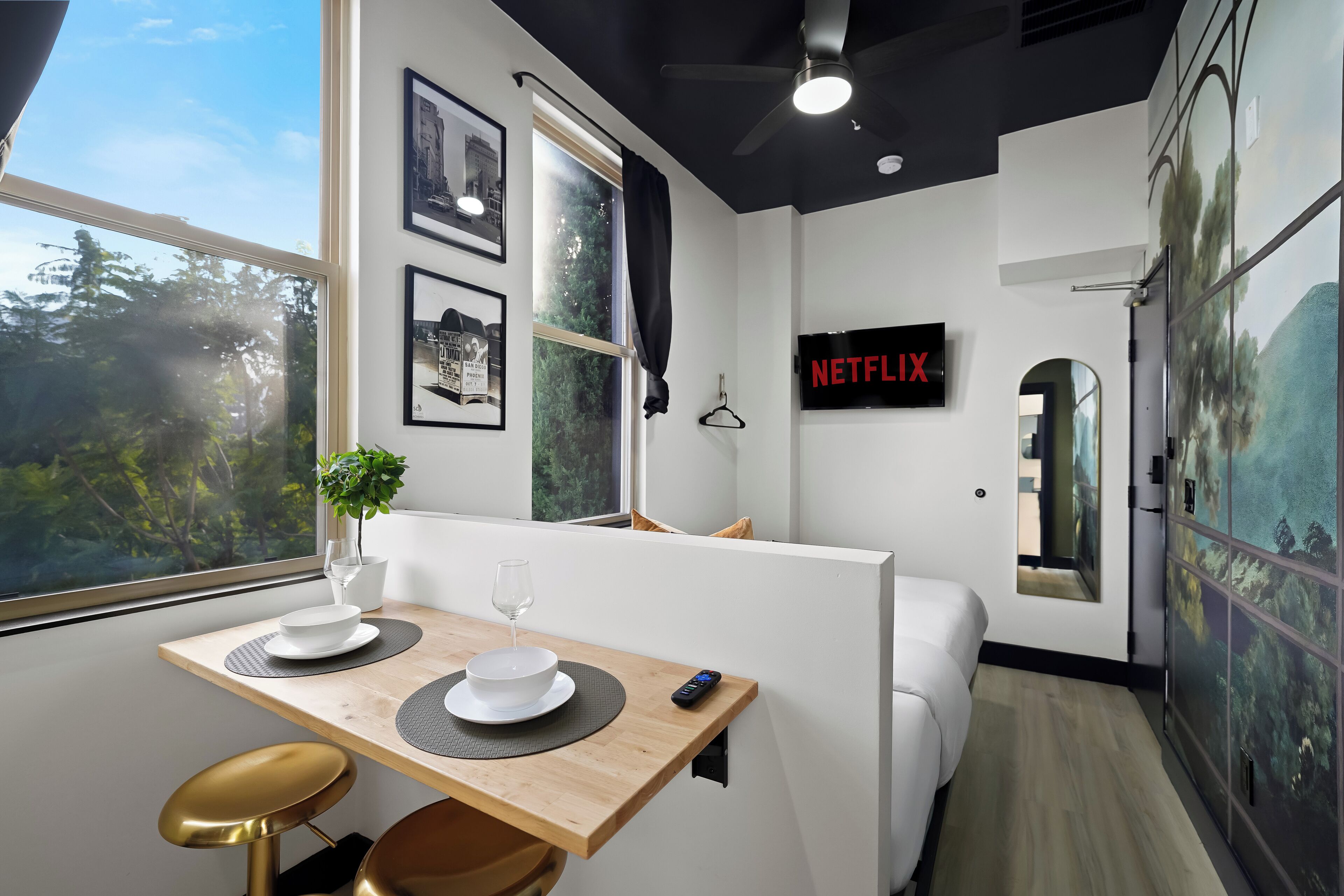 Een moderne kamer met een eethoek, een bank, een televisie en een groot raam.