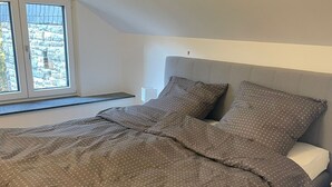 Un letto con una testiera grigia e un copripiumino grigio a pois.