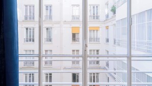 A view through a window of a multi-story building with balconies and windows. - Charming 1-Bedroom by Champ de Mars (Paris)
