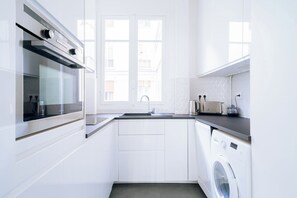 Cozinha moderna com forno embutido, pia e máquina de lavar.