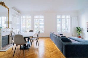 Ein großzügiger Wohnbereich mit Esstisch, Stühlen, einer Couch und großen Fenstern.