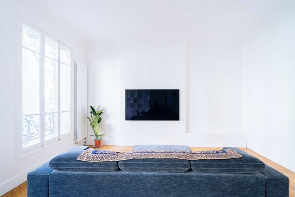Una sala de estar moderna con un sofá azul, una planta en maceta y una obra de arte enmarcada en la pared.