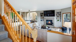 Uma sala de estar moderna com lareira, escada e área de jantar.