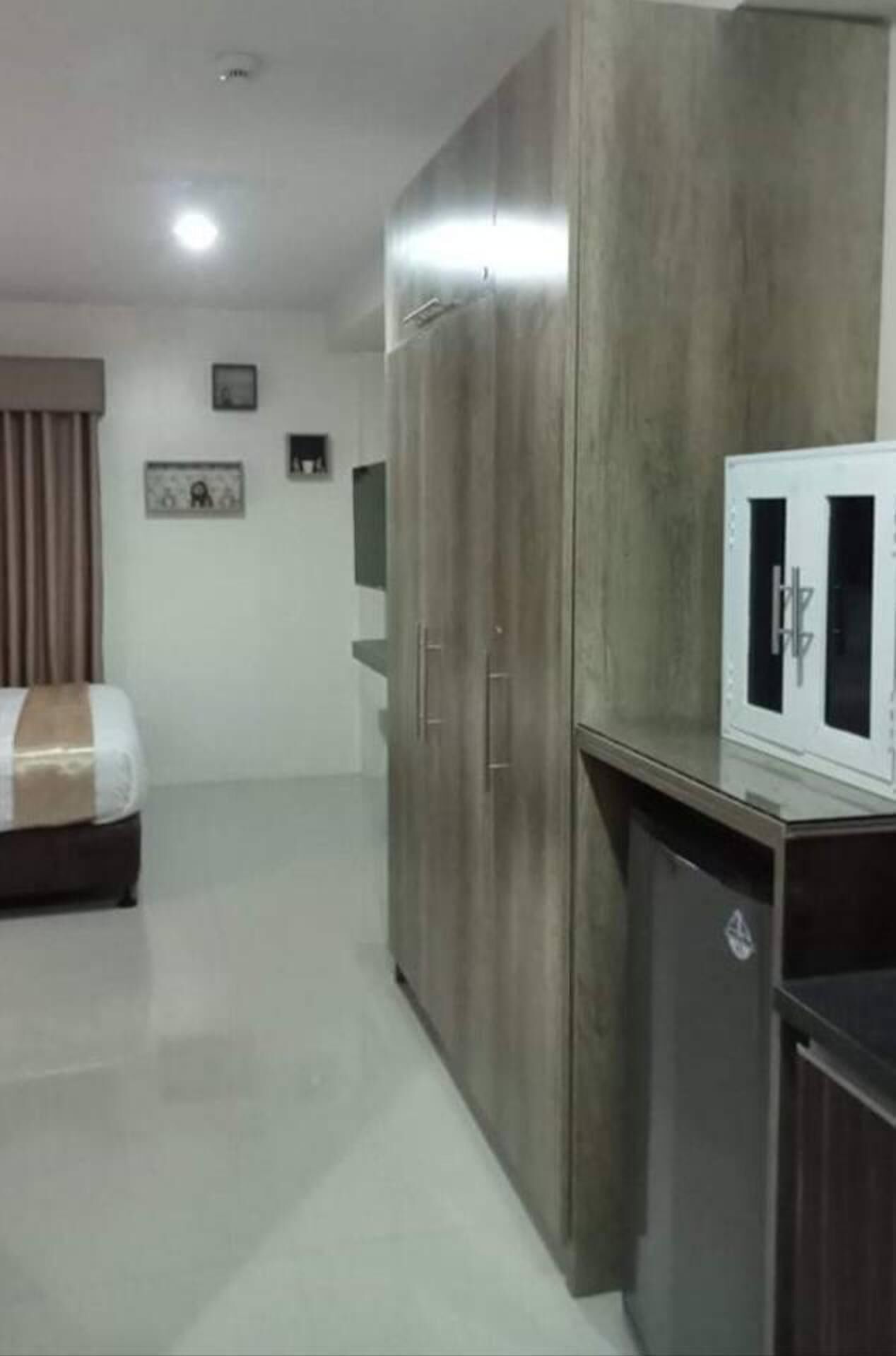 Quarto de hotel com cama, guarda-roupa e pequeno armário.