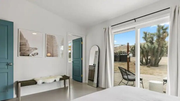 Una camera da letto con un letto, una panca, uno specchio e vista sull'esterno.