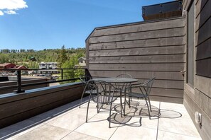 Ein Balkon mit Tisch und Stühlen, Blick auf ein Wohngebiet und ein Gebäude mit Holzverkleidung.