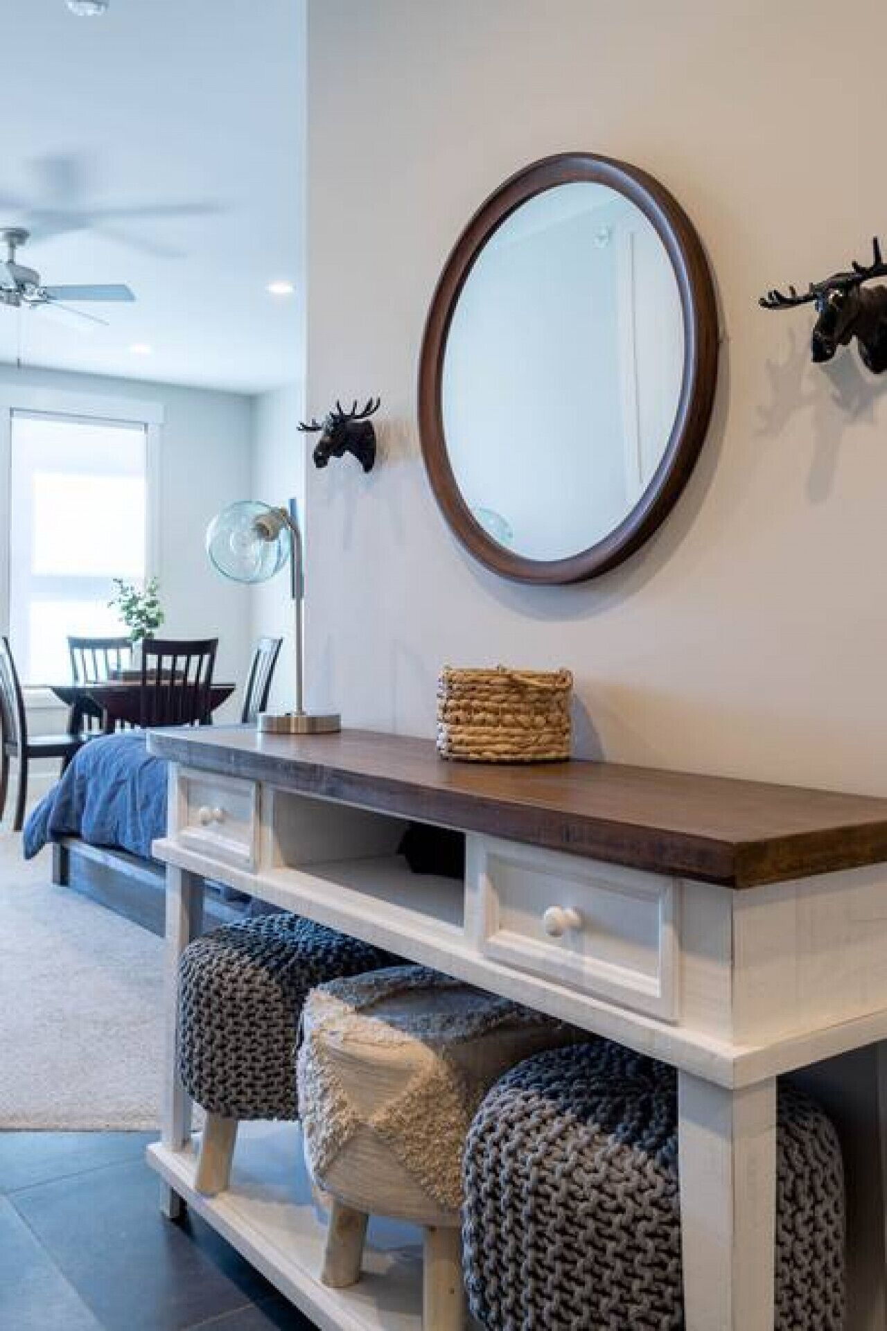 A modern interior with a wooden console table, a round mirror, and decorative wall art.