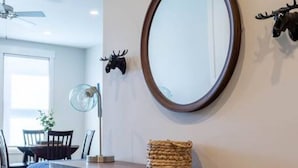 A modern interior with a wooden console table, a round mirror, and decorative wall art. - Mad Moose Retreat: Gorgeous Condo by Grand Lake! (Grand Lake)