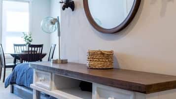 A modern interior with a wooden console table, a round mirror, and decorative wall art.