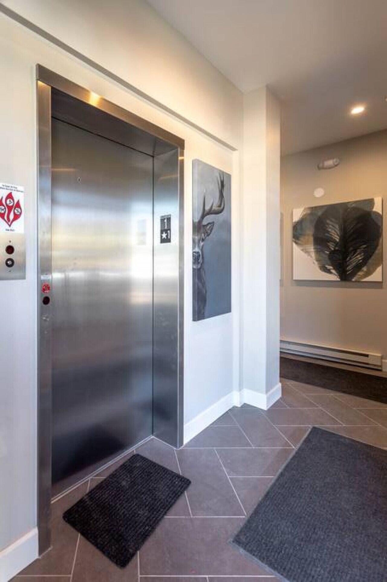 A modern elevator with a metallic finish, a control panel with emergency buttons, and a digital display.