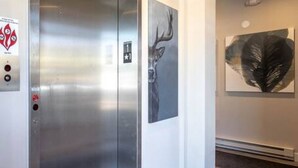 A modern elevator with a metallic finish, a control panel with emergency buttons, and a digital display. - Mad Moose Retreat: Gorgeous Condo by Grand Lake! (Grand Lake)