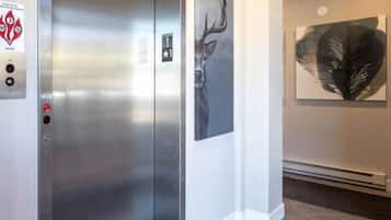 A modern elevator with a metallic finish, a control panel with emergency buttons, and a digital display.