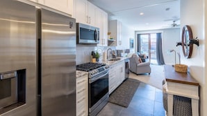 A modern kitchen with stainless steel appliances, a microwave, and a gas stove. There is a dining area with a sofa and a small table. - Mad Moose Retreat: Gorgeous Condo by Grand Lake! (Grand Lake)