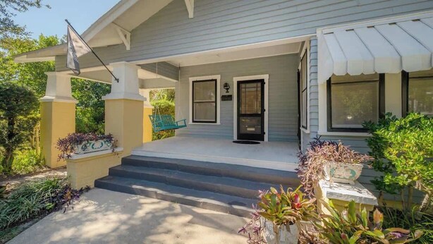 A house with a covered porch, steps leading to the front door, and a flag. - Historic Bungalow w/Game Room by Downtown Tampa! (Tampa)