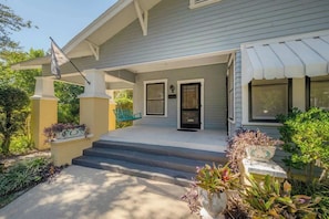 A house with a covered porch, steps leading to the front door, and a flag.