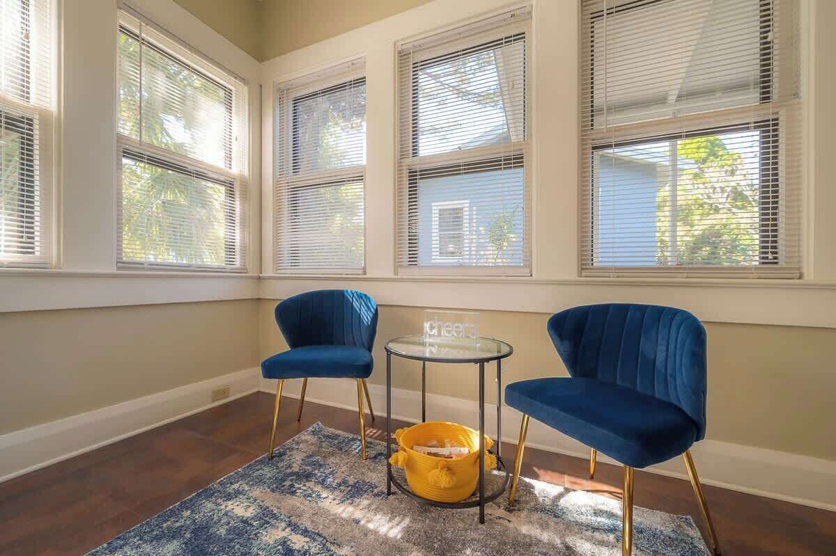 Une pièce avec trois chaises bleues, une petite table et un panier jaune posé sur un tapis à motifs.