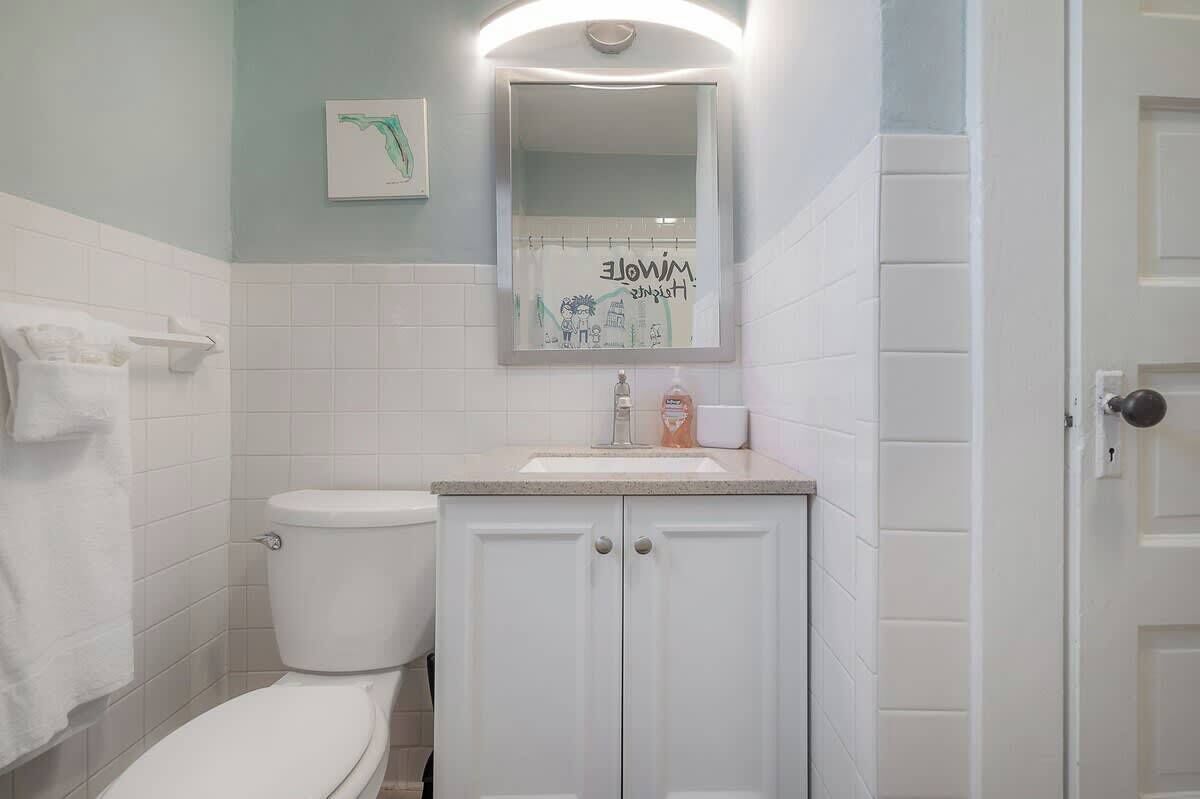 A bathroom with a white toilet, a sink with a mirror above it, and a towel rack.