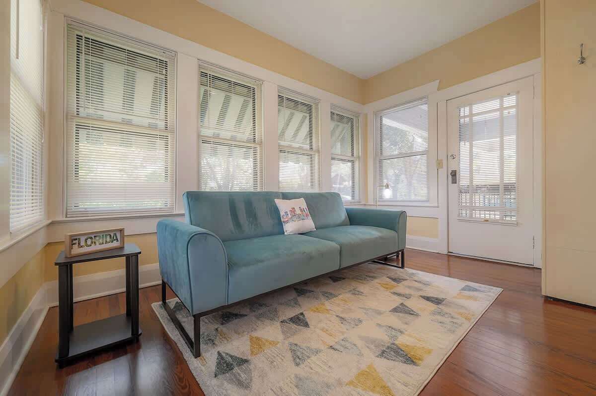 A living room with a teal sofa, a patterned rug, and a small table with a 'FLORIDA' sign.