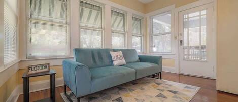 Una sala de estar con un sofá color turquesa, un tapete estampado y una mesita con un letrero que dice 'FLORIDA'.