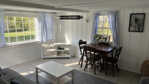 Een eetruimte met een witte tafel en stoelen, een witte console en een schilderij aan de muur.