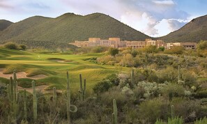 A golf course with cacti and a building in the background.