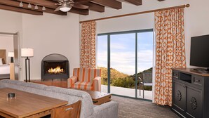 A modern hotel room with a fireplace, a dining area, a sofa, and a television. - Starr Pass Spring Golf Retreat - April 12-15 - 1 Bedroom Condo (Tucson)