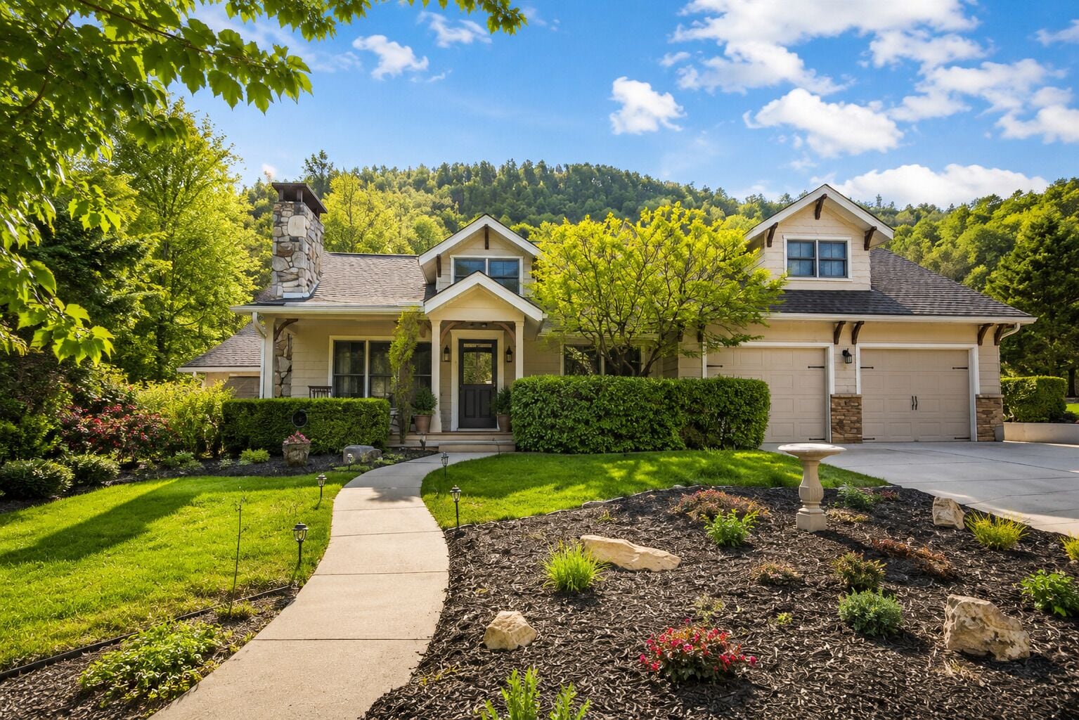 A two-story house with a stone chimney, a front porch, and a driveway leading to a garage.