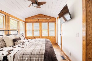 A bedroom with a bed, wooden walls, a ceiling fan, and large windows. - Golden Acres Ranch Hot Tub,Game Room, Creek & Mtn View. 8m from DT Highlands (Highlands)