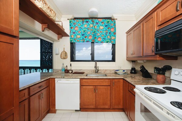 A kitchen with wooden cabinets, a white dishwasher, a stove, and a window with a blue curtain.