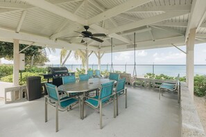 An outdoor patio with a grill, seating, and a view of the ocean.