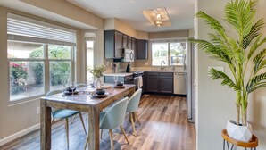 A modern kitchen with dark cabinets, a wooden dining table, and a potted plant. - Garden view home - near major higways w/high chair, pack&play, baby bathtub ways (Phoenix)
