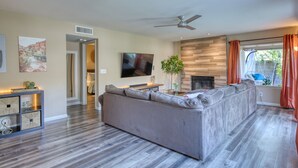A modern living room with a large gray sectional sofa, a flat-screen TV, a fireplace, and a ceiling fan. - Garden view home - near major higways w/high chair, pack&play, baby bathtub ways (Phoenix)