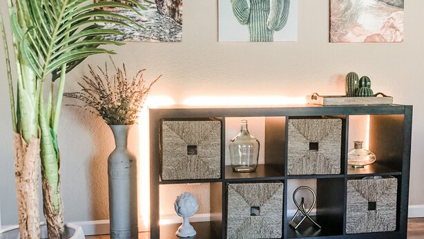 A living room with a dark wood floor, a potted plant, a round wooden table, and a black console table with decorative boxes and a vase. - Garden view home - near major higways w/high chair, pack&play, baby bathtub ways (Phoenix)