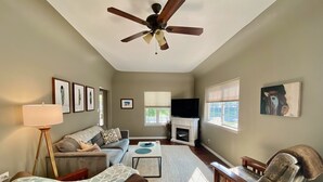 Un salon doté d’un ventilateur de plafond, d’une cheminée, d’un canapé, d’une table basse et d’un téléviseur.