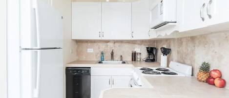 A modern kitchen with white cabinets, a dishwasher, a stove, and a sink.