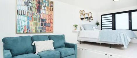 A modern living room with a teal sofa, a coffee table, and a colorful abstract painting on the wall.