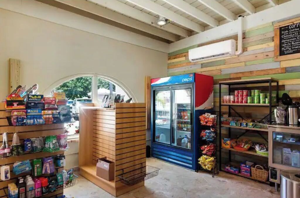A store with a Pepsi refrigerator, shelves stocked with snacks, and a wooden display unit.