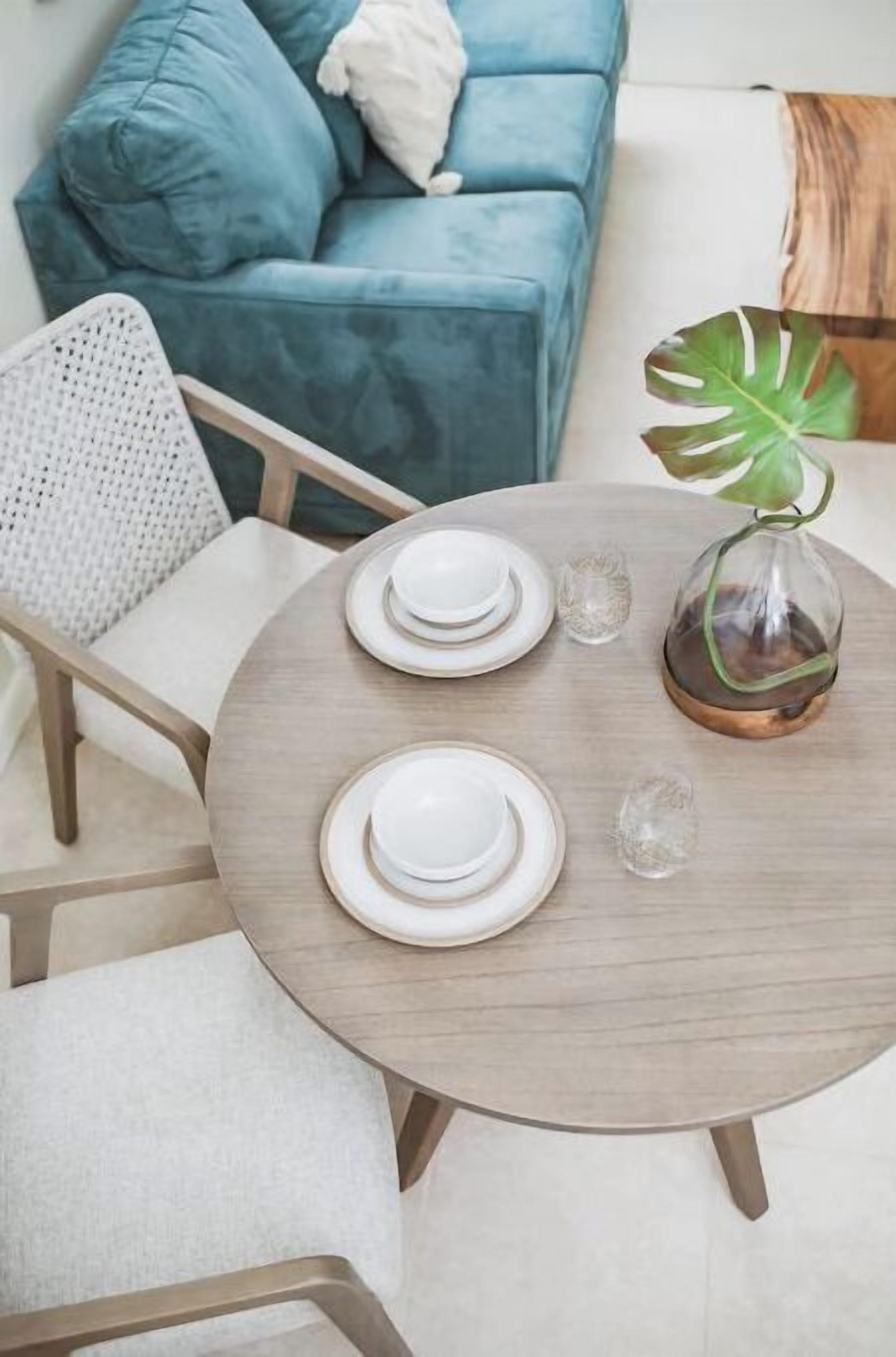 A dining table set with plates and a glass vase with a plant.
