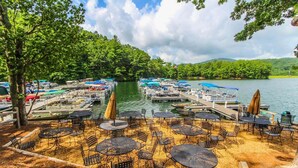 A lakeside patio with outdoor seating and a marina in the background. - Golf Club Villas (Marble Hill)