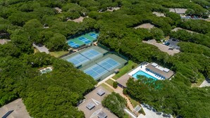 Ovenudblik over et boligområde med flere tennisbaner, en swimmingpool og grøn bevoksning omkring.