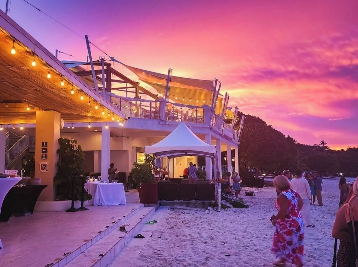 A beachside venue with a covered outdoor area, a white tent, and a dining setup.