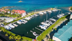 An aerial view of a marina with multiple boats docked, surrounded by buildings and greenery. - Charming Beach Condo w/ Balcony (Smith Bay)
