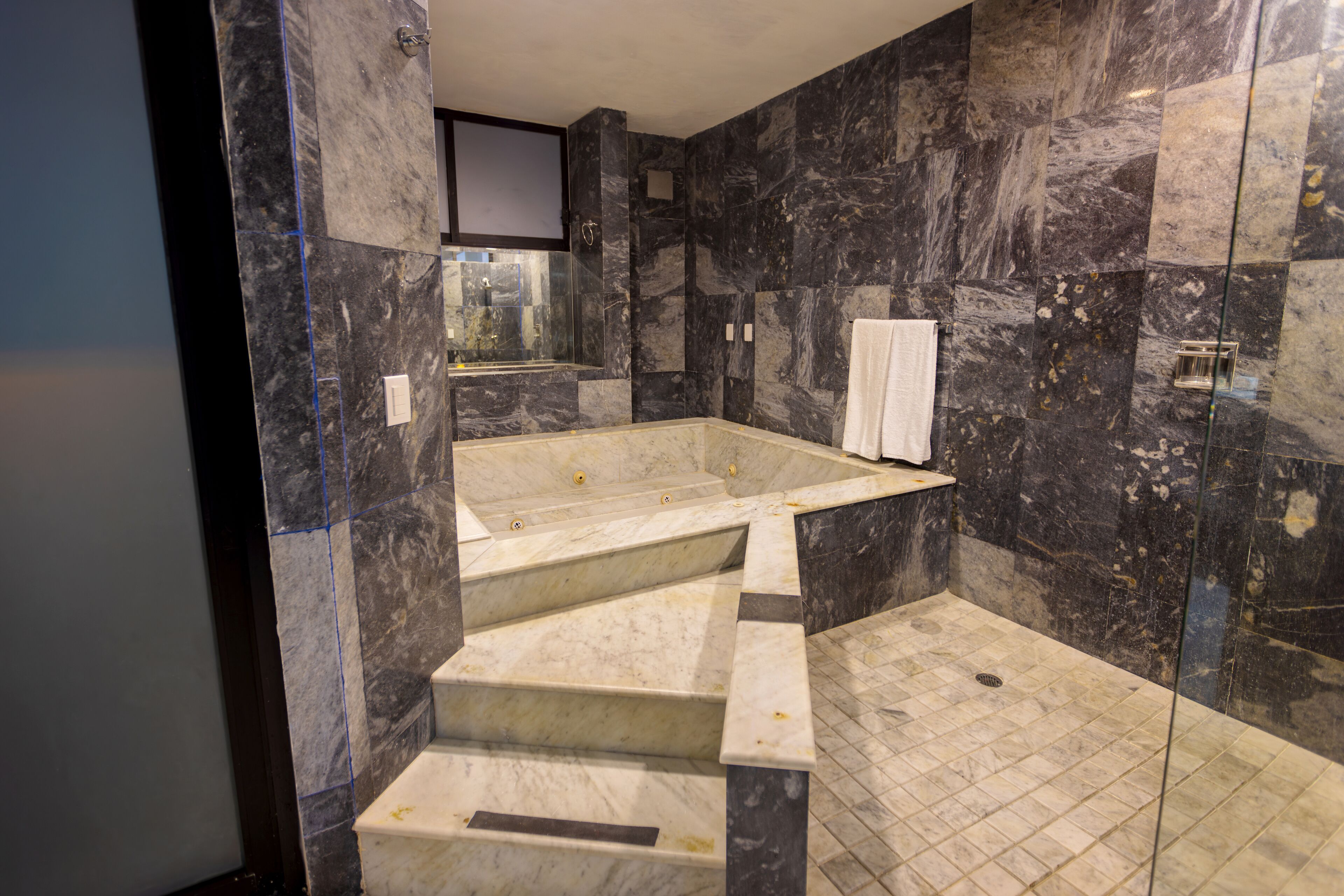 Un baño moderno con suelo de mármol, una bañera independiente y una cabina de ducha de vidrio.