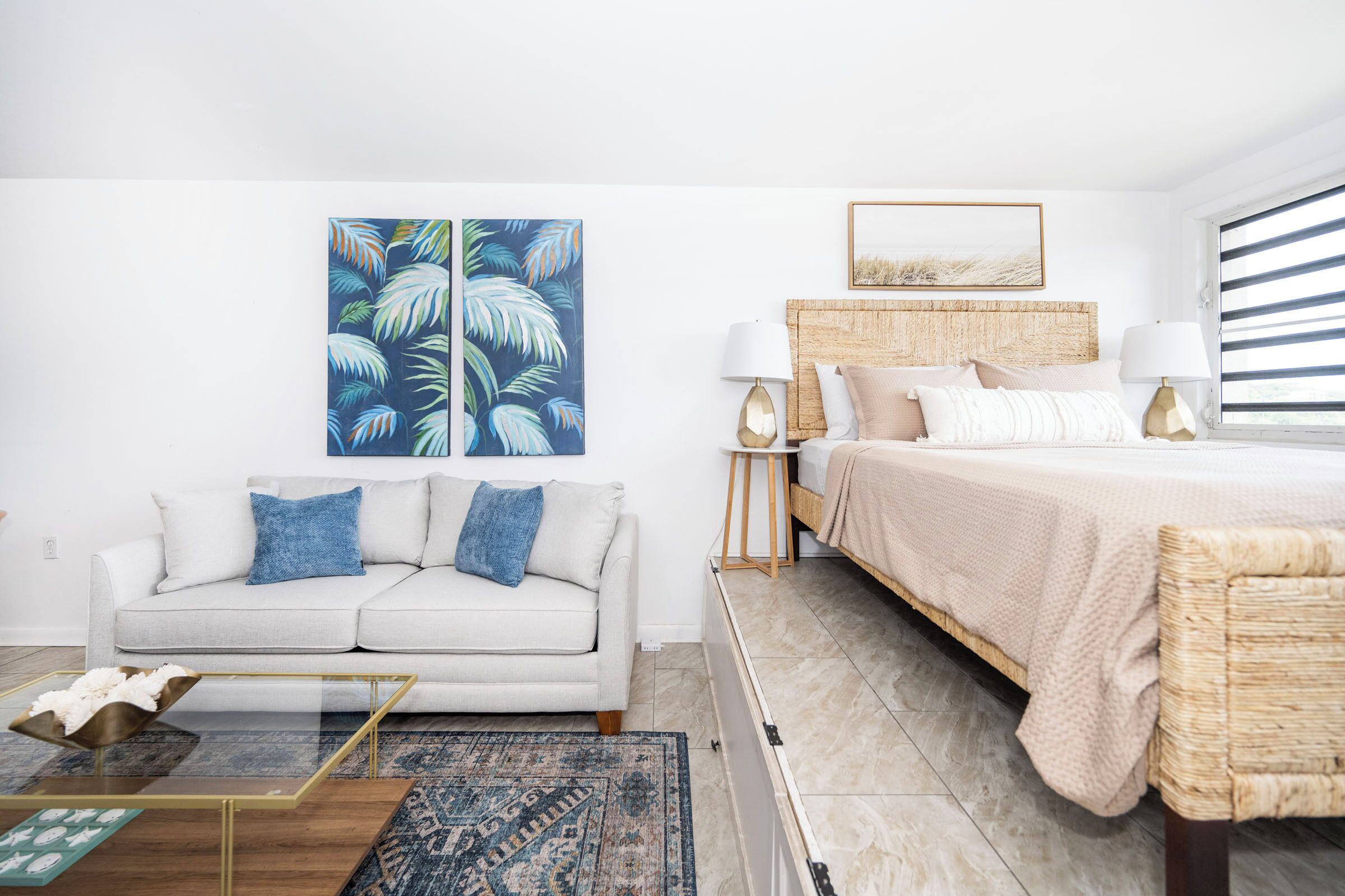Un dormitorio moderno con una cama, un sofá, una mesita de centro y un cuadro en la pared.